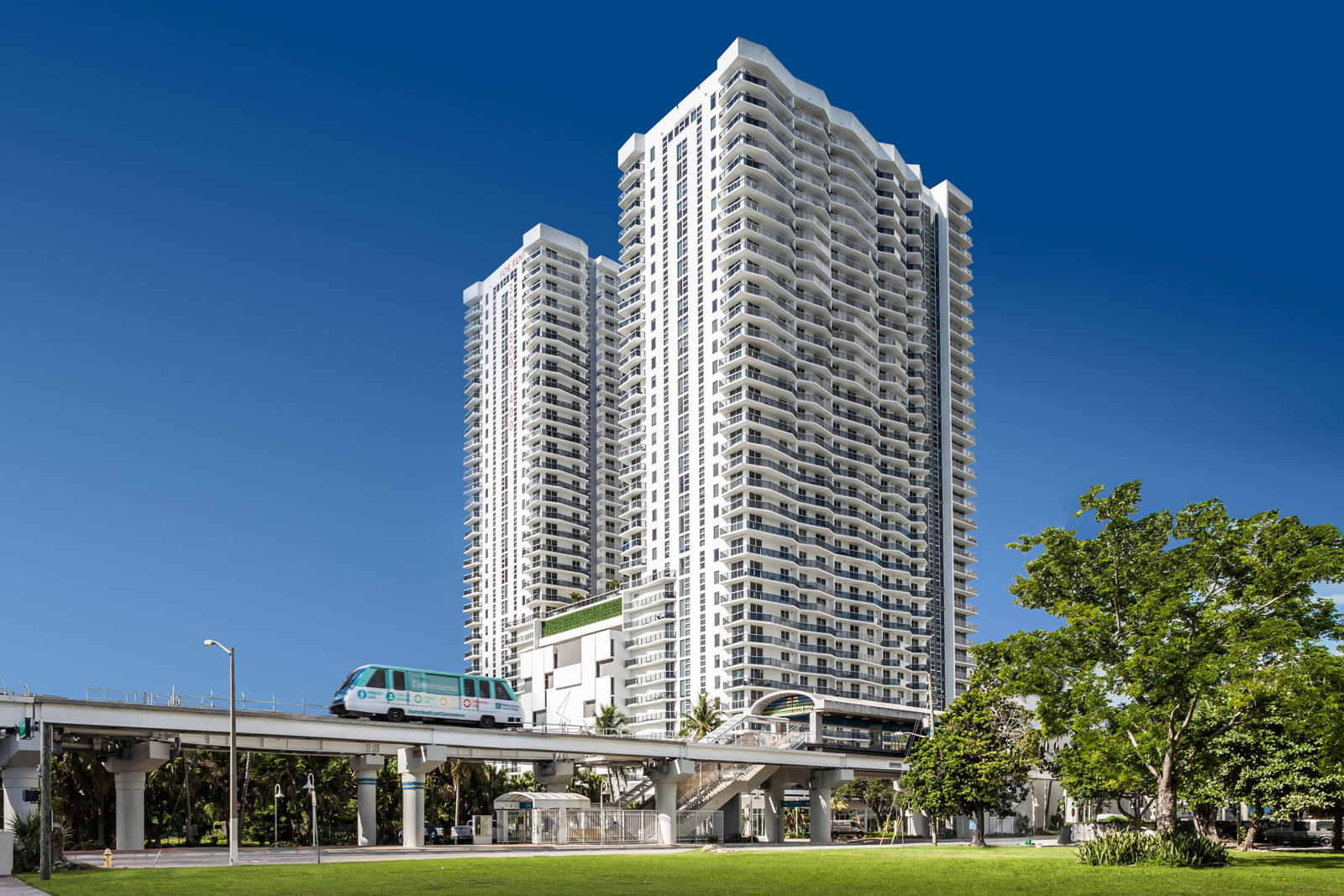 A tall building at Square Station in Miami FL with a transit system in front.