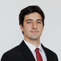 Man in business suit with a red tie, smiling.